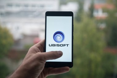 Üstünde belgili tanımlık perde smartphone parmak ile Ubisoft logolu tutan adam.