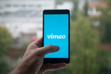 Üstünde belgili tanımlık perde smartphone parmak ile Vimeo logolu tutan adam.