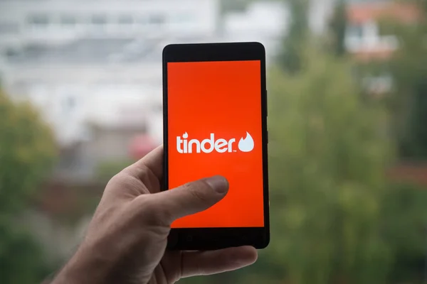 Man holding smartphone with Tinder logo with the finger on the screen. — Stock Photo, Image