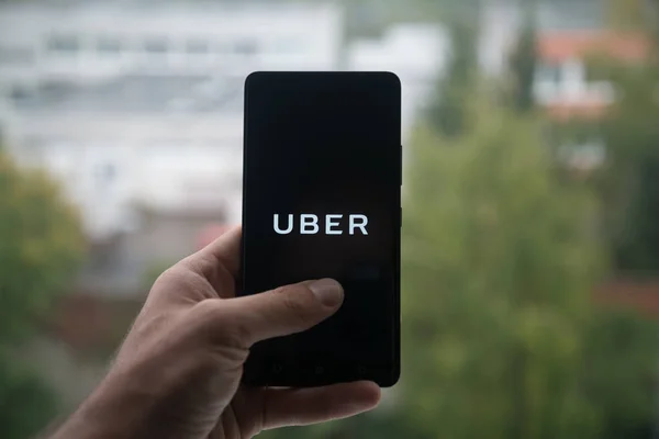 Man met smartphone met Uber logo met de vinger op het scherm. — Stockfoto
