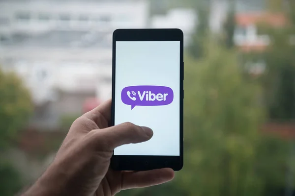 Hombre sosteniendo teléfono inteligente con el logotipo de Viber con el dedo en la pantalla . — Foto de Stock