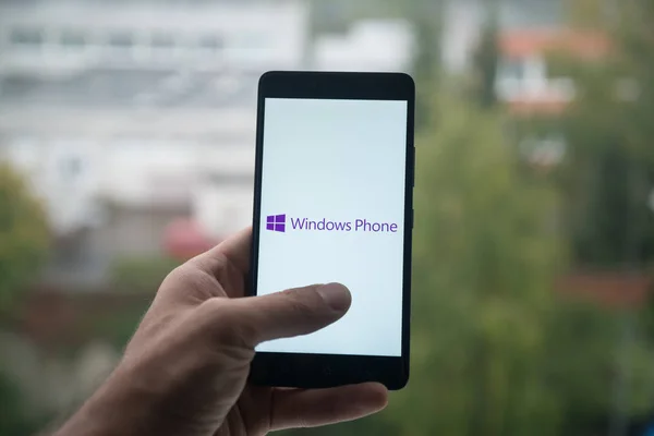 Hombre sosteniendo el teléfono inteligente con el logotipo del teléfono con Windows con el dedo en la pantalla . —  Fotos de Stock