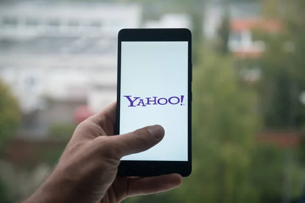 Hombre sosteniendo teléfono inteligente con el logotipo de Yahoo con el dedo en la pantalla . —  Fotos de Stock