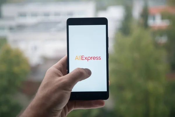 Чоловік тримає смартфон з логотипом Aliexpress з пальця на екран. — стокове фото