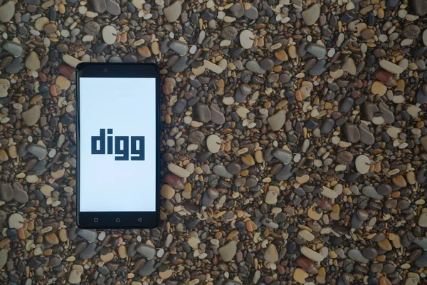 Digg logotipo en el teléfono inteligente en el fondo de piedras pequeñas — Foto de Stock