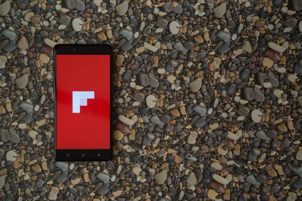 Flipboard-Logo auf Smartphone auf Hintergrund aus kleinen Steinen — Stockfoto