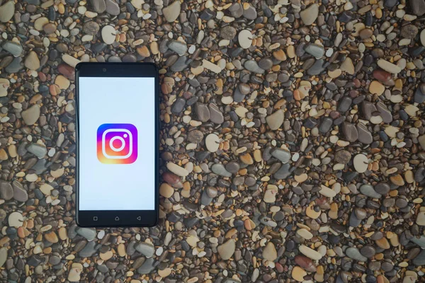 Instagram logo on smartphone on background of small stones — Stock Photo, Image