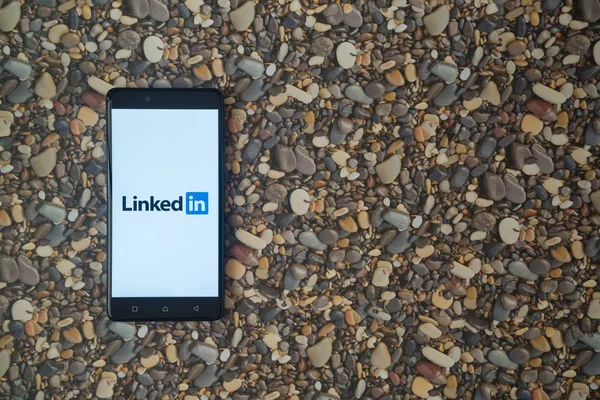 Logotipo Linkedin en el teléfono inteligente en el fondo de piedras pequeñas — Foto de Stock