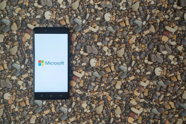 Microsoft logo on smartphone on background of small stones — Stock Photo, Image