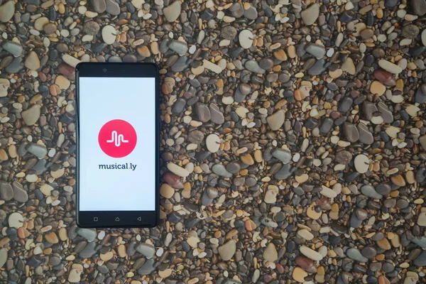 Musical.ly logo on smartphone on background of small stones — Stock Photo, Image
