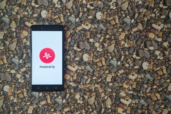 Logotipo Musical.ly en el teléfono inteligente en el fondo de piedras pequeñas — Foto de Stock