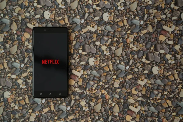 Netflix-Logo auf Smartphone auf Hintergrund aus kleinen Steinen — Stockfoto