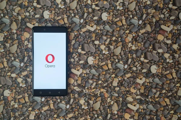 Opera mini z logiem na smartphone na tle małe kamienie — Zdjęcie stockowe