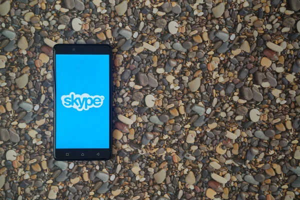 Logotipo de Skype en el teléfono inteligente en el fondo de piedras pequeñas — Foto de Stock