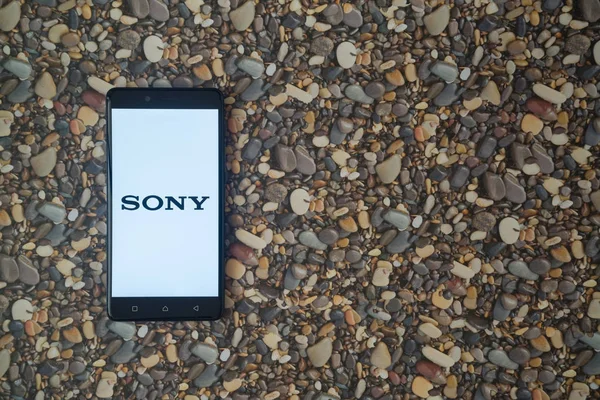 Logotipo da Sony no smartphone no fundo de pequenas pedras — Fotografia de Stock