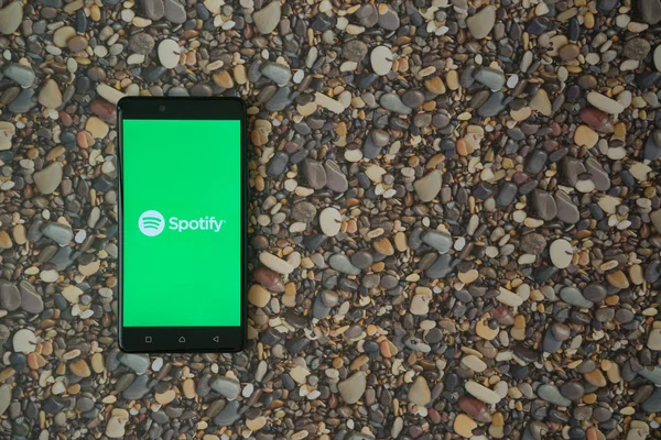 Spotify-Logo auf Smartphone auf Hintergrund aus kleinen Steinen — Stockfoto