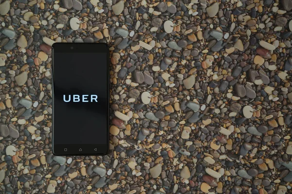 Логотип Uber на смартфоне на фоне небольших камней — стоковое фото