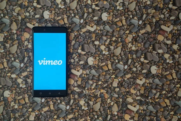 Logotipo de Vimeo en el teléfono inteligente en el fondo de piedras pequeñas — Foto de Stock