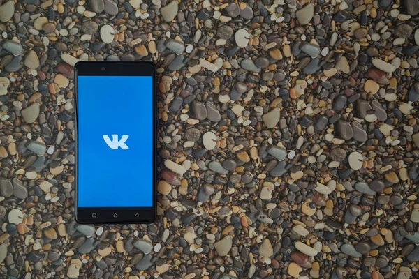 VKontakte logo na smartphone na tle małe kamienie — Zdjęcie stockowe