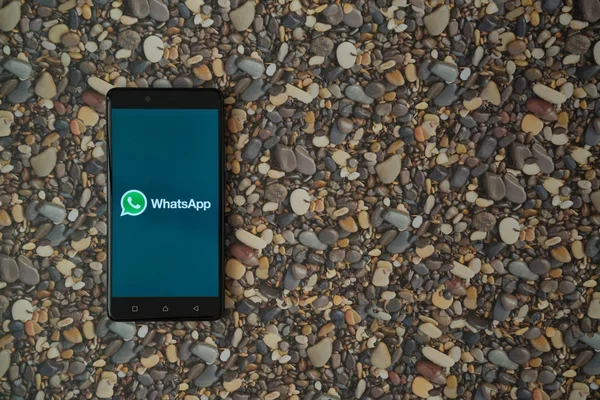 Whatsapp logo smartphone cep telefonu ile küçük taş zemin üzerine — Stok fotoğraf
