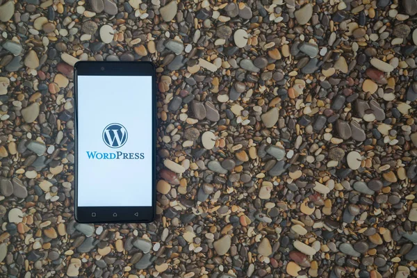 Logo de Wordpress en el teléfono inteligente en el fondo de piedras pequeñas — Foto de Stock