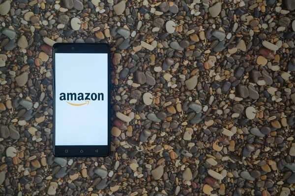 Logotipo de Amazon en el teléfono inteligente sobre fondo de piedras pequeñas — Foto de Stock