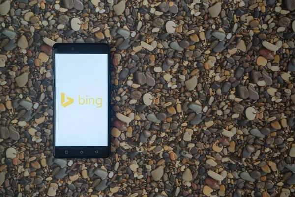 Logotipo de Microsoft Bing en el teléfono inteligente en el fondo de piedras pequeñas —  Fotos de Stock