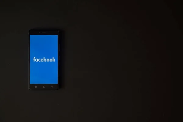 Logotipo do Facebook na tela do smartphone no fundo preto — Fotografia de Stock