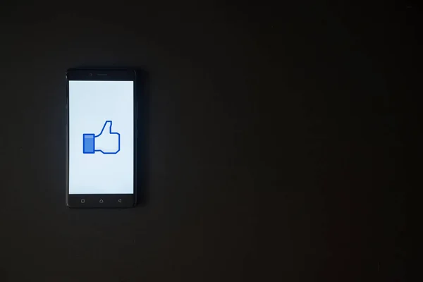 Facebook нравится логотип на экране смартфона на черном фоне — стоковое фото