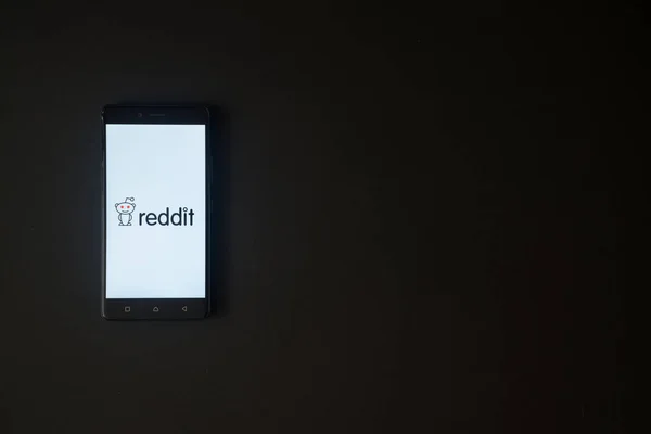 Logotipo do Reddit na tela do smartphone no fundo preto — Fotografia de Stock