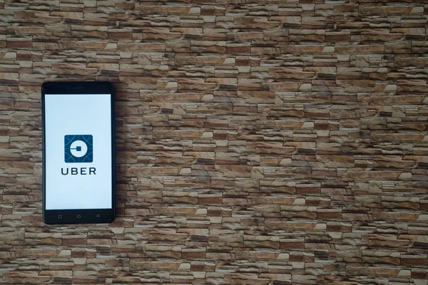 Logotipo Uber na tela do smartphone no fundo de pedra — Fotografia de Stock