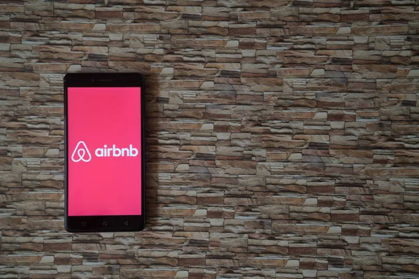 Airbnb logo on smartphone screen on stone facing background — Stock Photo, Image