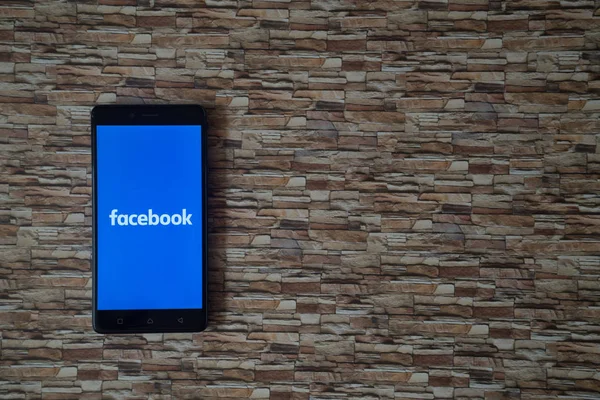 Facebook logo üstünde smartphone perde arka plan karşı karşıya taş — Stok fotoğraf
