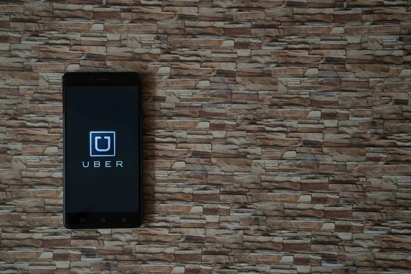 Logo Uber sullo schermo dello smartphone su sfondo fronte pietra — Foto Stock