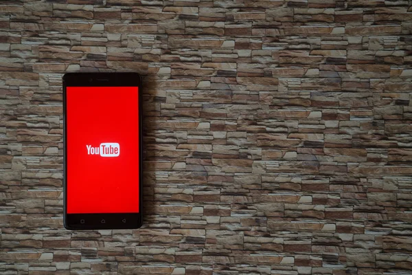 YouTube logo op smartphone scherm op steen geconfronteerd met achtergrond — Stockfoto