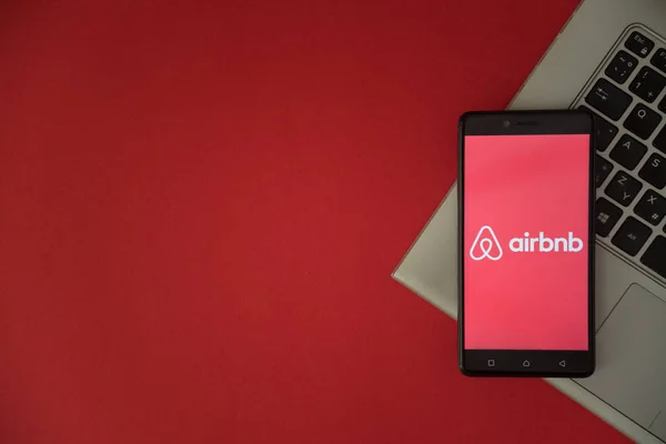 Logo Airbnb sullo schermo dello smartphone posizionato sulla tastiera del portatile . — Foto Stock