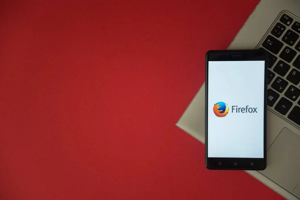 Logotipo de Mozilla firefox en la pantalla del teléfono inteligente colocado en el teclado portátil . — Foto de Stock