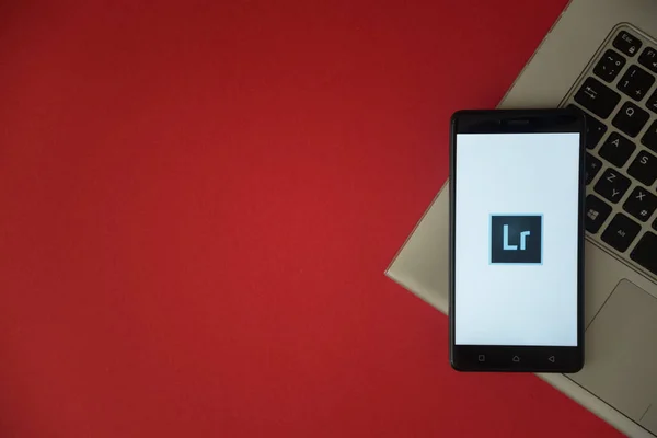 Adobe photoshop lightroom logotipo na tela do smartphone colocado no teclado do laptop . — Fotografia de Stock