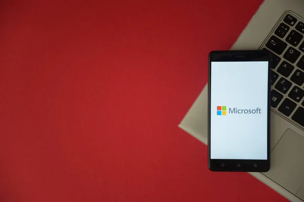 Logo firmy Microsoft, na ekranie smartfonu, umieszczone na klawiaturze laptopa. — Zdjęcie stockowe