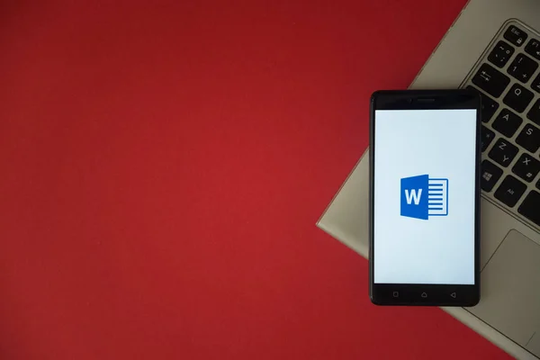 Microsoft office word 徽标放在笔记本键盘的智能手机屏幕上. — 图库照片