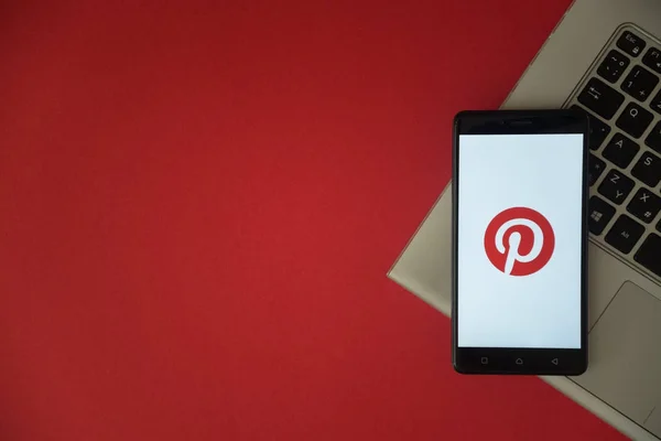 Pinterest logo op smartphone scherm geplaatst op laptop toetsenbord. — Stockfoto