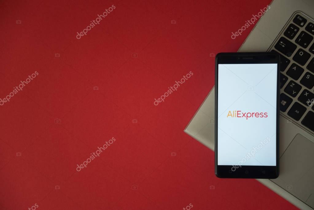 London, United Kingdom, October 23, 2017: Aliexpress logo on smartphone screen placed on laptop keyboard. Empty place to write information with red background.