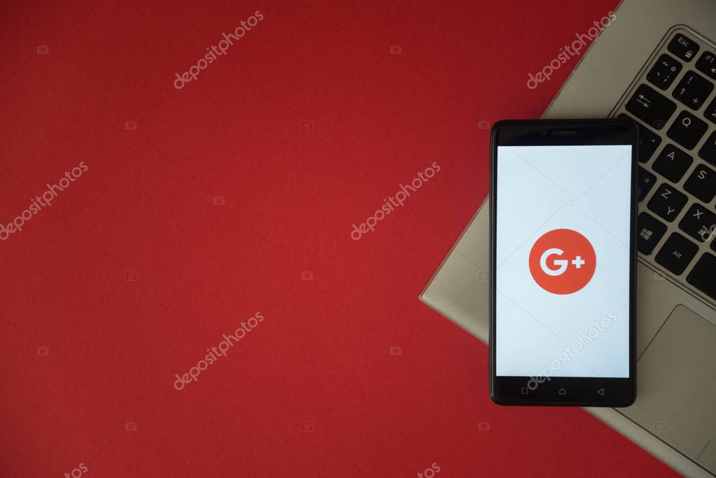 London, United Kingdom, October 23, 2017: Google plus logo on smartphone screen placed on laptop keyboard. Empty place to write information with red background.
