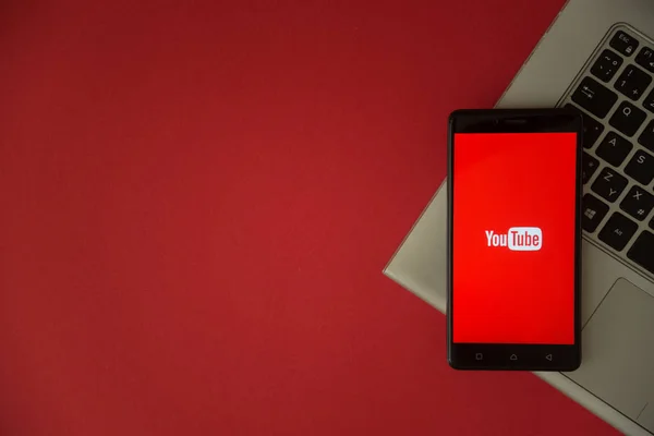 Logotipo do YouTube na tela do smartphone colocada no teclado do laptop . — Fotografia de Stock