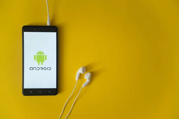 Logo de Android en la pantalla del teléfono inteligente sobre fondo amarillo — Foto de Stock