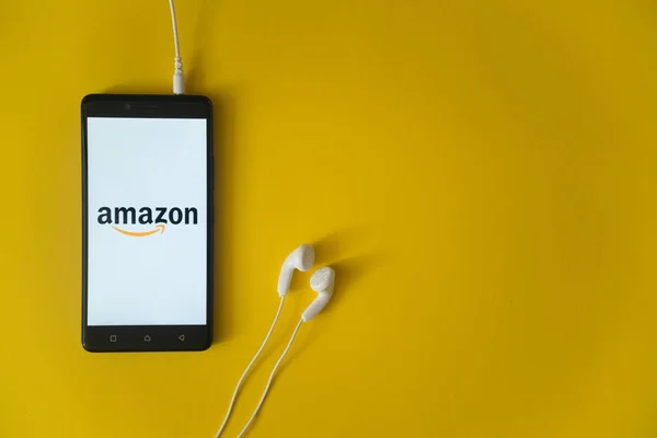 Amazon logo na ekranie smartfona na żółtym tle — Zdjęcie stockowe