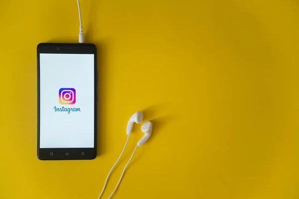 Instagram logo on smartphone screen on yellow background — Stock Photo, Image