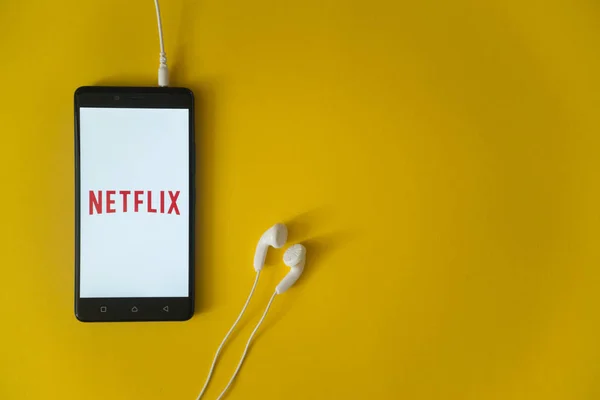Netflix логотип на екрані смартфона на жовтому фоні — стокове фото
