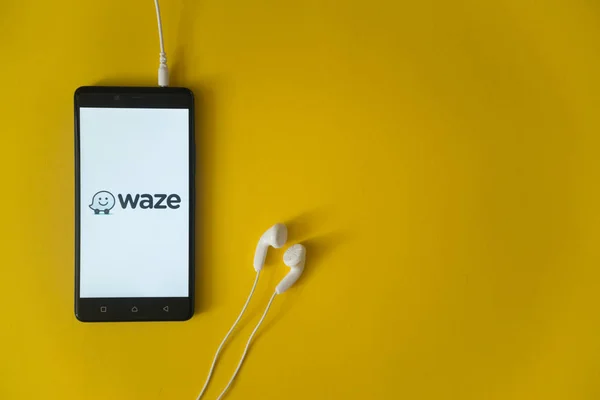 Waze logo na ekranie smartfona na żółtym tle — Zdjęcie stockowe