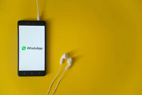 Logotipo de Whatsapp en la pantalla del teléfono inteligente sobre fondo amarillo — Foto de Stock